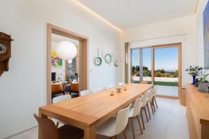 uma sala de jantar com mesa e cadeiras de madeira em Grandiose Brac Villa Villa Mediteranea 6 Bedrooms Infinity Pool & Outdoor Tv em Škrip