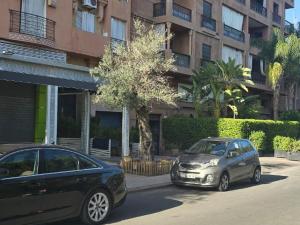 zwei Autos auf einem Parkplatz vor einem Gebäude geparkt in der Unterkunft Appartement Moderne Gueliz in Marrakesch