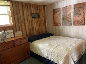 a bedroom with a bed and a dresser and maps on the wall at Peaceful Cayuta Lake Cottage with early check in in Alpine