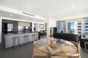 una cucina e un soggiorno con tavolo in vetro di Artique Surfers Paradise - Official a Gold Coast Altre 168 foto