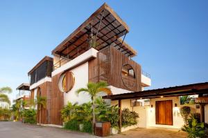 a house with a wooden facade with palm trees at Baliwood Residence Villas by BREIG in Munggu