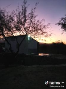une maison au soleil couchant derrière un arbre dans l'établissement Finca de montaña agua Gracian, à Pomancillo