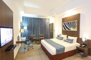 a hotel room with a bed and a flat screen tv at Best Western Elyon Colombo in Colombo