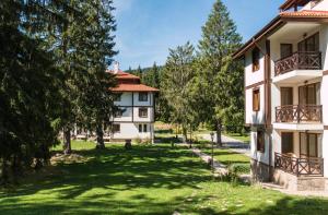 an apartment building with a yard with trees at Mountain Lake Hotel in Smolyan