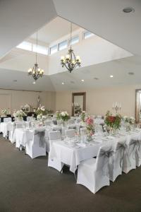 ein Zimmer mit weißen Tischen, weißen Stühlen und Blumen in der Unterkunft Oscars Hotel and Cafe Bar in Ballarat