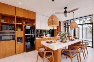 a kitchen with a large island with wooden cabinets at Baliwood Residence Villas by BREIG in Munggu