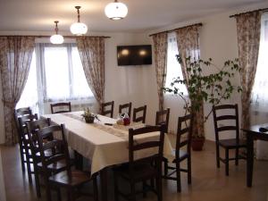 a dining room with a table and chairs and windows at Pensiunea Obcina Mare in Cacica