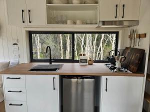 a kitchen with a counter with a sink and a window at Tiny Lola in Huskisson