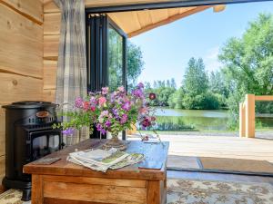 a vase of flowers on a wooden table with a fireplace at Kingfisher Cabin in Croft