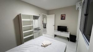 a white bedroom with a bed and a television at Apartamento Térreo Completo! Com Ótima Localização in Fortaleza