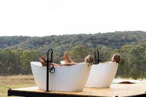 two people laying in a bath tub on a dock at Tiny Maggie in Rylstone