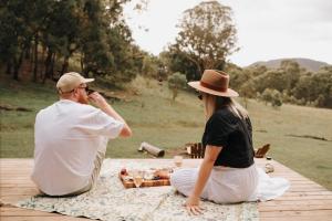 a man and a woman sitting on a picnic table at Tiny Maggie in Rylstone