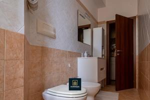 un baño con inodoro y espejo en Dominique Comfort Apartment, en Reggio Calabria