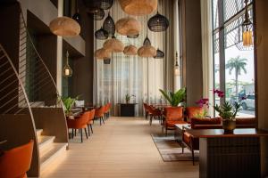 a restaurant with orange chairs and tables and lamps at SOMA HOTEL Riverside in Phnom Penh