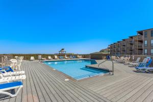 a swimming pool with lounge chairs on a wooden deck at C102A - Dawn at Duck in Duck