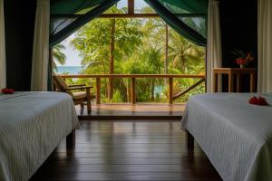 two beds in a room with a view of the ocean at La Leona Eco Lodge in Carate