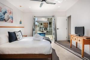 马奇McG Mudgee -Hamptons inspired- with a splash pool的卧室里有一张白色的床和一台电视