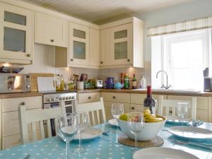 a kitchen with a table with a bowl of fruit and wine glasses at Shore Cottage in Arnisdale