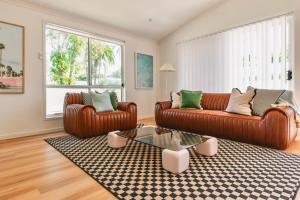 a living room with two leather couches and a coffee table at The Little Tropicana in Byron Bay