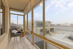 グレネルグにあるBeachside 2-Bed Apartment with Balcony Viewsのバルコニー(椅子付)、大きな窓が備わります。
