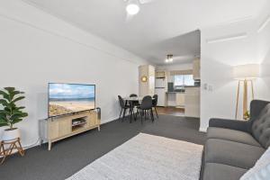 グレネルグにあるBeachside 2-Bed Apartment with Balcony Viewsのソファ、テレビ、テーブルのあるリビングルーム
