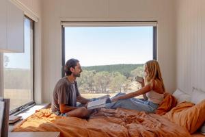 Ein Mann und eine Frau sitzen auf einem Bett und lesen Bücher. in der Unterkunft Tiny Rosie in Mount Crawford
