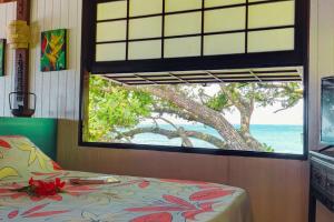 a bedroom with a window looking out at the ocean at TAHITI Tamanu House - Séjour Bord de mer, Plage privée, TV, Wifi, Hôte Polynésienne in Papehee
