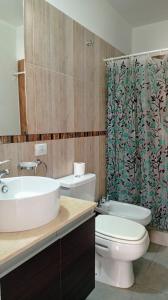 een badkamer met een wastafel, een toilet en een douchegordijn bij Exelente departamento en Carlos Paz in Villa Carlos Paz