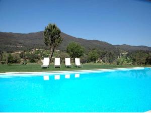 a swimming pool with chairs and a tree and mountains at Beautifully Restored Ponte De Lima Farm House 6 Bedrooms Quinta Fornelos Private Pool & Surrounded By Hectares Of Vineyards in Ponte de Lima