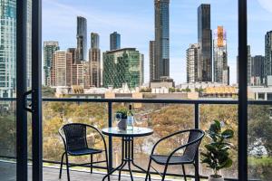 a table and chairs on a balcony with a view of a city at Modern 2B2B Apt near Crown with Parking and City Views in Melbourne