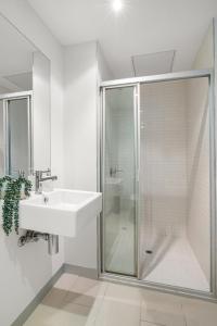 a white bathroom with a sink and a shower at Modern 2B2B Apt near Crown with Parking and City Views in Melbourne