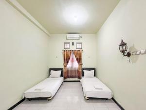 Dos camas en una habitación con ventana. en Hotel Permai Syariah RedPartner Sananwetan Blitar, en Karangtengah