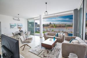 ein Wohnzimmer mit Sofas und ein Esszimmer in der Unterkunft Villa Olive Thalassa, Brand New, Luxury 3Bdr Protaras Villa With Private Pool in Protaras