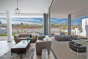 ein Wohnzimmer mit Sofas und Tischen und einem großen Fenster in der Unterkunft Villa Olive Thalassa, Brand New, Luxury 3Bdr Protaras Villa With Private Pool in Protaras