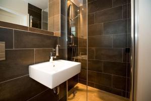 a bathroom with a white sink and black tiles at Haus-Alster in Westerland (Sylt) +22 photos