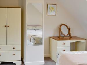 ein Schlafzimmer mit einem Spiegel, einem Bett und einer Kommode in der Unterkunft Bluebell Cottage in Wootton Fitzpaine