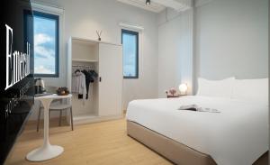 a white bedroom with a large white bed and a desk at Emerald Hotel Residence in Phnom Penh