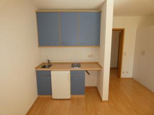 a small kitchen with blue cabinets and a wooden floor at WuP Living Apartment am Stadtwald TG Parkplatz in Augsburg