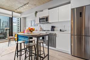 a kitchen with white cabinets and a counter with bar stools at Vibrant PopArt downtown suite, comfy and stylish! in Calgary