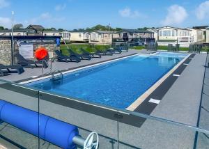a swimming pool at a apartment complex with chairs at White Tower Holiday Park in Llandwrog