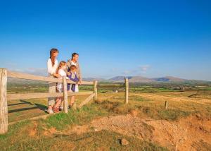 a family standing next to a fence on a hill at White Tower Holiday Park in Llandwrog