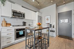 a kitchen with white cabinets and a island with bar stools at Vibrant PopArt downtown suite, comfy and stylish! in Calgary +26 photos
