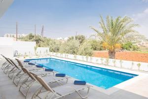einen Pool mit Chaiselongues und einem Pool in der Unterkunft Villa Manta Platina - Brand New Luxury 3 Bedroom Protaras Villa in Protaras + 12 Fotos