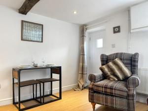 a living room with a chair and a table at Cricketers Cottage in Ipstones