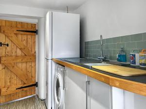 a kitchen with a white refrigerator and a sink at Cricketers Cottage in Ipstones