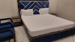 a bedroom with a bed with a blue headboard at Karachi Guest House University Rd in Karachi