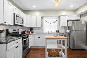 Una cocina con gabinetes blancos y un refrigerador de acero inoxidable. en Walk to Churchill & Cardinal Stadium Near SDE, en Louisville