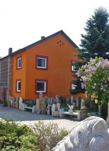 an orange house with a cemetery in front of it at Ferienwohnung beim Steinmetzmeister im Quarzwerk in Lautertal