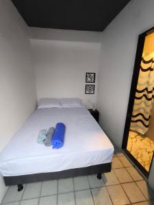 a white bed with a blue pillow on it at Mini Suite Comforto in Garanhuns