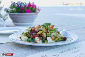 a plate of salad on a table with a bowl of flowers at Kekrifalia Hotel in Skala